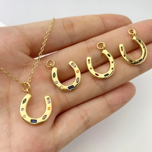Détail de pendentifs fer à cheval sertis de zircons colorés sur métal doré poli