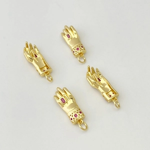 Détail de quatre pendentifs main dorés avec pierres de zircon rouges et motifs de poignet