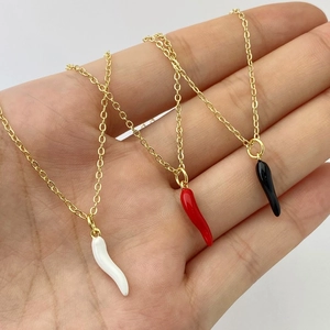 Detailed macro view of three chili pepper pendants in white, red and black with gold chains