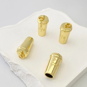 Détail de quatre mini pendentifs en forme de tasse à café dorée avec gravure