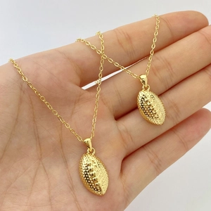 Detailed view of hand-held gold rugby ball pendant necklaces with slender link chains