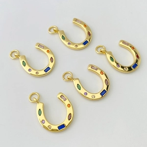 Détail de pendentifs en fer à cheval dorés avec zircons multicolores sertis arc-en-ciel