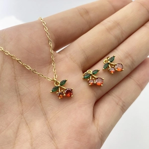 Detail of cherry jewelry set with gold plating and red gemstones on a hand