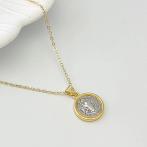 Detailed macro view of two-tone gold and silver Saint Benedict medal necklace pendant