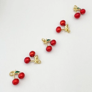 Vue détaillée de cinq breloques cerises miniatures avec finition rouge et accents dorés