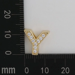 Macro view of gold plated Y-shaped charm with white cubic zirconia on measurement scale