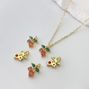 Detailed view of cherry pendant necklace with green leaf and orange-red gemstone inlay