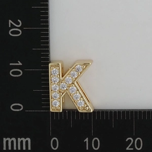Macro shot of gold letter K pendant with clear cubic zirconia on a scale background