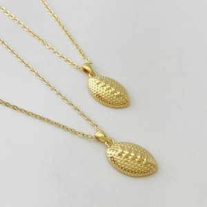 Detail of golden American football pendants with textured surface and cross chain