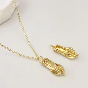 Détail d'un collier pendentif main vintage avec zircon rouge et finition dorée