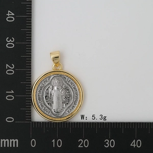 Close-up of Saint Benedict two-tone medal pendant with measurement scale on white background