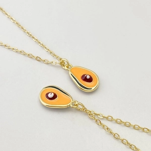 Vue macro détaillée de pendentifs avocat dorés avec incrustation d'émail orange et chaînes