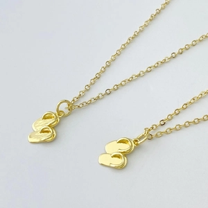 Détails des pendentifs tongs dorées sur une chaîne à maillons fins en or