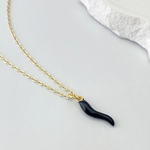 Detailed view of a gold O-chain necklace with a black Italian Cornetto pepper pendant