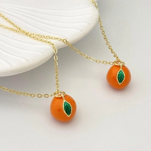 Détail d'un pendentif en forme d'orange sur une fine chaîne de collier dorée