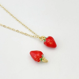 Détail macro d'un pendentif fraise rouge avec chaîne dorée pour colliers et bijoux DIY