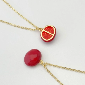 Vue détaillée des colliers dorés avec pendentifs fraise rouges et finition émail brillant