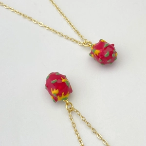 Détail de colliers pendentifs pitaya avec chaîne dorée et finition en émail coloré