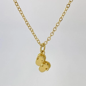 Gros plan d'un pendentif tong en or avec finition polie sur une chaîne croisée simple