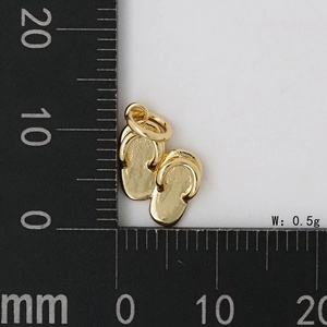Vue macro d'un pendentif tong doré de 0,5 g sur une règle pour référence de taille précise