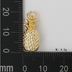 Vue détaillée d'un pendentif ananas doré de 4,5g avec des écailles à côté d'une règle