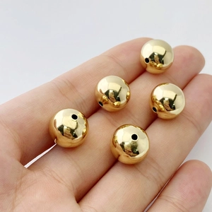 Primo piano di cinque perline rotonde dorate lucide con foro centrale per gioielli DIY
