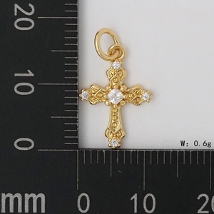 Vue macro d'un mini pendentif croix en or avec zircons sertis sur une échelle