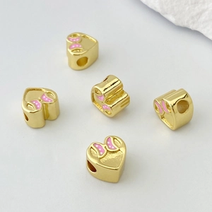 Dettaglio macro di perline a cuore placcate in oro con fiocchi rosa per gioielli
