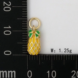 Détail d'un pendentif ananas en émail de 1,25g avec mesures sur une règle noire