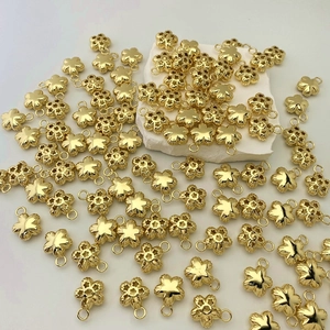 Detailed close-up of gold-plated five-petal flower charms with delicate hollow and solid designs