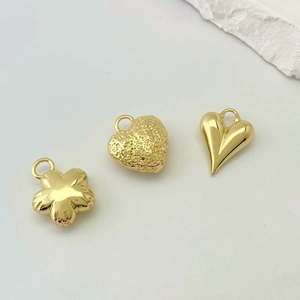 Detailed close-up of gold heart and flower pendants with polished and hammered textures