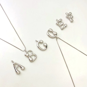 Macro shot of silver letter pendants A-F with sparkling cubic zirconia on box chains