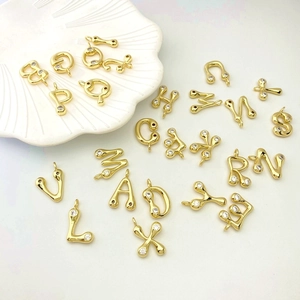 Close-up of golden letter pendants with cubic zirconia in a white shell dish
