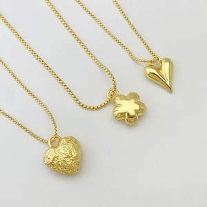 Detailed view of three gold necklaces featuring textured heart and flower shaped pendants