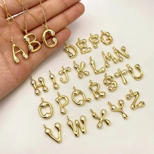 Close-up of alphabet letter pendants set with shimmering micro-zirconia in gold finish