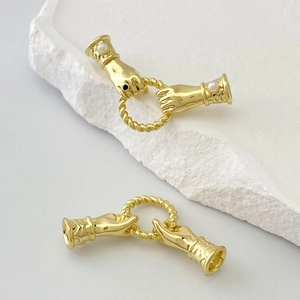Dettaglio dei connettori a mano in oro vintage con perle e anello a treccia per gioielli