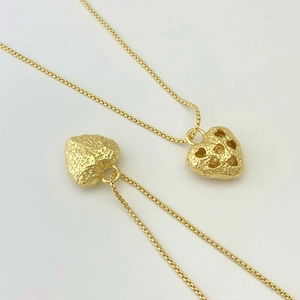 Close-up of golden heart necklaces with hammer texture and box chain detail