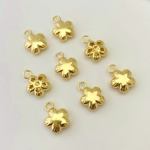 Detailed macro view of 8 gold flower pendants with mirror finish and star hollow backs