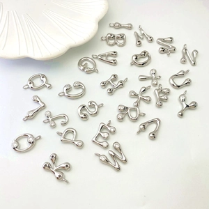 Detailed macro view of sparkling silver letter pendants with micro-zirconia inlay on white