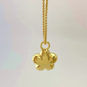 Detailed close-up of golden five-petal flower pendant with polished mirror finish and chain