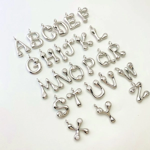 Collection of 26 English letter pendants with fluid lines and inlaid zircons on white background