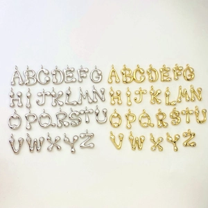 Macro detail of alphabet pendants with micro-zirconia in gold and silver finishes