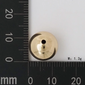 Dettaglio di una perla tonda in metallo dorato da 12mm con peso 1,3g e misura su righello