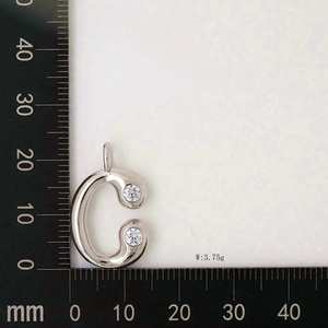 Detail view of silver letter C pendant with zircon stones on a measuring ruler