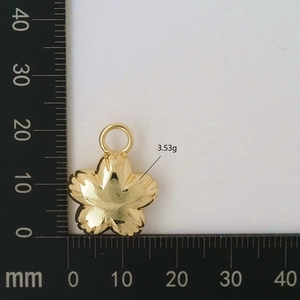 Detail view of a golden five-petal flower pendant showing a 20mm diameter on a scale