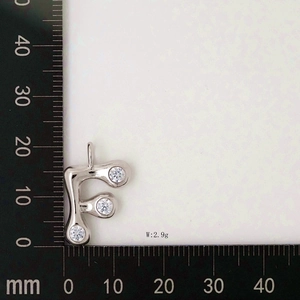 Macro shot of silver letter F pendant with zircon stones showing 20mm height on scale