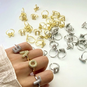 Macro detail of gold and silver letter rings featuring micro-pave cubic zirconia settings