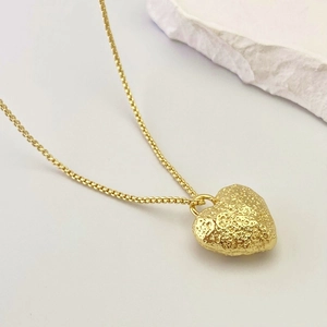 Elegant gold heart pendant necklace featuring unique textured lava finish on a box chain