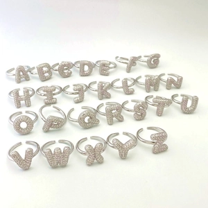 Close-up of 26 alphabet open rings with cubic zirconia pavé setting on white background