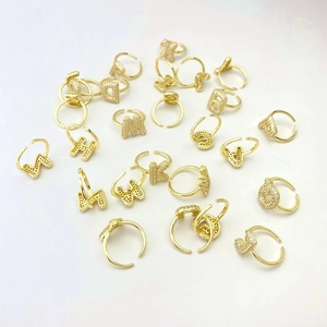 Close-up of gold-plated initial rings set with micro-pave cubic zirconia on white background